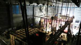 Theatre workers: a photograph of a theatre stage including the rafters, rigging and scaffolding structures above and behind the theatre stage.