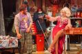 A dishelleved man in rumpled clothes (Dash Kruck) and a glamous, laughing, blonde-haired Dolly Parton in a low cut red dress (Tricia Paoluccio) in a scene from the musical 'Here You Come Again'.