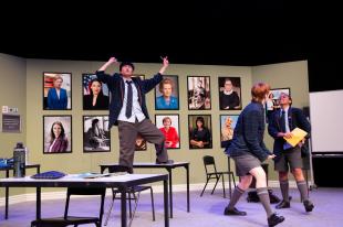 A classroom scene in Trophy Boys, with three students. One is standing on a table.