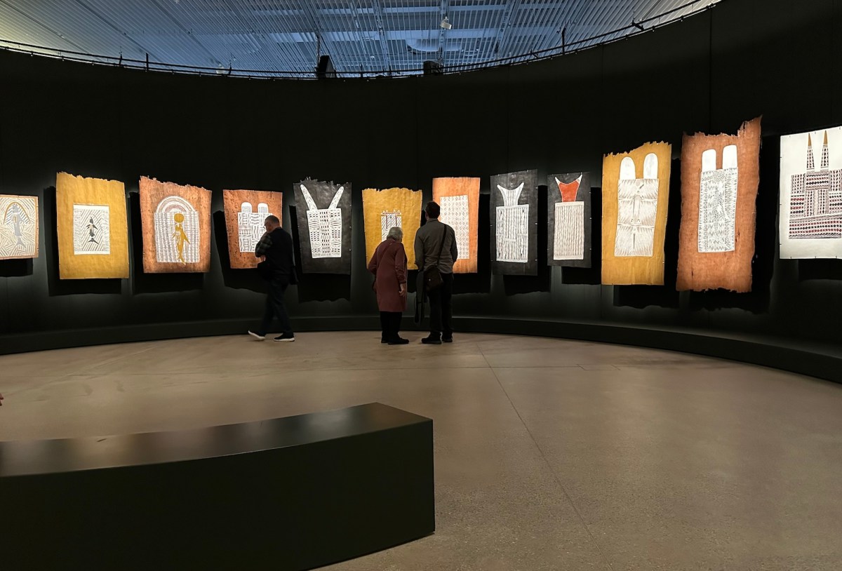 Gallery with black painted walls displaying Australian Aboriginal bark paintings. Yirrkala
