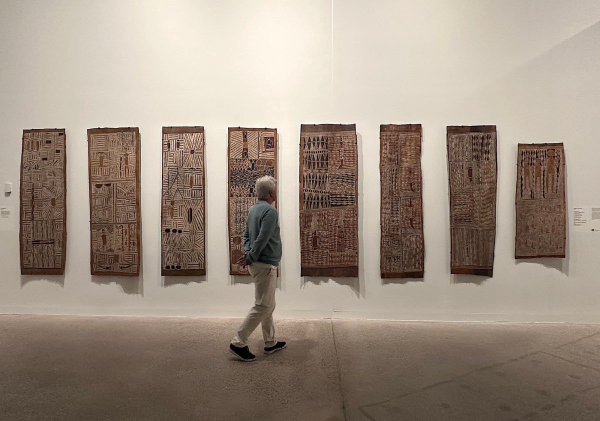 Man looking at traditional Aboriginal Australian bank paintings in gallery setting. Yirrkala