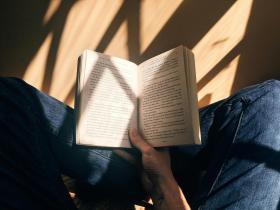 A person sitting cross-legged holding a book open. Publishing after book rejection