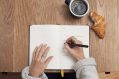 A view from above as someone handwrites into a notebook, thereby avoiding any issues of AI copyright.