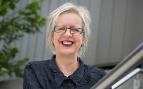 A middle aged woman with short blonde hair and a black shirt. she is smiling. Vale Judith Isherwood.