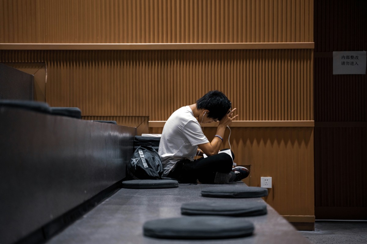 Young man with white t-shirt in lecture theatre at educational facility. University cuts