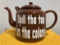 a brown enamelled steel tea pot with white writing on the side that says SPILL THE TEA ON THE COLONY. Kerry Klimm, CIAF 2025 Art Fair Showcase