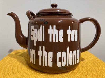 a brown enamelled steel tea pot with white writing on the side that says SPILL THE TEA ON THE COLONY. Kerry Klimm, CIAF 2025 Art Fair Showcase