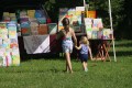 A young girl is holding the hand of a toddler girl. They are walking towards some picture books.