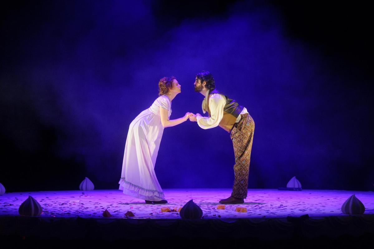 A man and a woman in Regency costume are holding hands and facing one another in Pride and Prejudice.