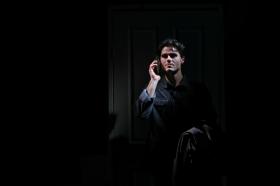 A man with holding a phone in his ear in the dark in Dial M for Murder.