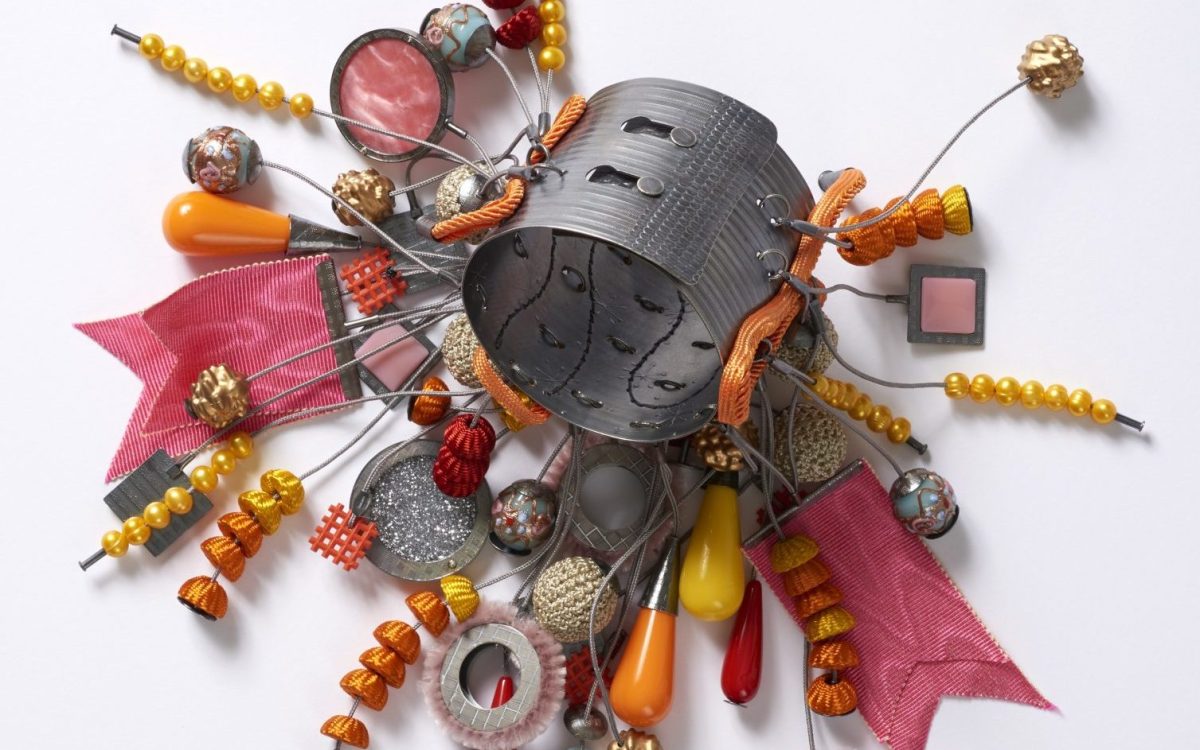 A mixed-media bangle with different elements like beads and wire dangling off it, in colours of red, orange and yellow. Free exhibitions NSW.