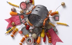 A mixed-media bangle with different elements like beads and wire dangling off it, in colours of red, orange and yellow. Free exhibitions NSW.