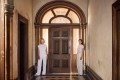 Photo of two middle-aged white women standing on both sides of the door of a historic mansion, Villa Alba.