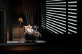 A man, Ian Stenlake, sitting in a chair near a shuttered blind in The 39 Steps.