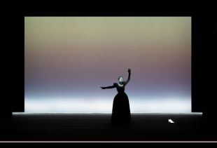 Isabelle Huppert in 'Mary Said What She Said,' exclusive to the 2026 Adelaide Festival. The photograph depicts Huppert in a stylised stage performance, her white-painted face distorted and her arms thrown out as she cries aloud in grief or anger.