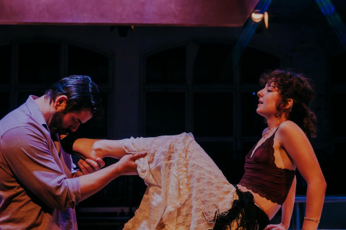 A man cradling a woman's leg in a production of Miss Julie.