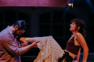 A man cradling a woman's leg in a production of Miss Julie.