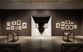 Small black and white photographers arranged in two clusters on either side of two mirrors, each with a small photographer in the centre. Man Ray and Max Dupain at Heide.