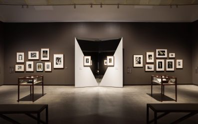 Small black and white photographers arranged in two clusters on either side of two mirrors, each with a small photographer in the centre. Man Ray and Max Dupain at Heide.