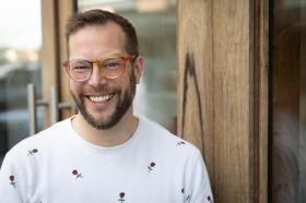 A bearded man with glasses and a white t-shirt smiling. Michael Earp, new owner of The Little Bookroom.