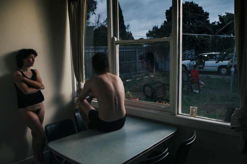 a couple in a room with moody lighting and an large window to the street. Photo Sydney