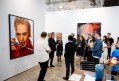 Group of people having a tour in an art fair booth displaying photography