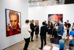 Group of people having a tour in an art fair booth displaying photography