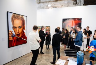 Group of people having a tour in an art fair booth displaying photography