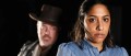 A publicity image for The Street Theatre's production of 'The Chosen Vessel', a new Aboriginal Gothic play by Dylan Van Den Berg. The photo depicts an Aboriginal woman staring at the camera; a white man stands ominously behind her, disappearing into the shadows.