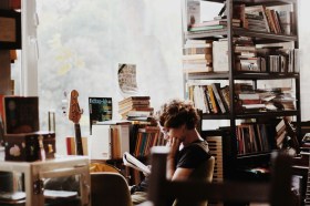 A woman reading surrounded by a library. Best new fiction in Australia, September 2025.