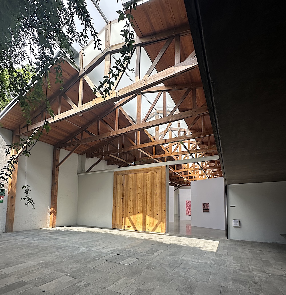 Exterior view of a contemporary art gallery with open roof and trusses. Mexico City
