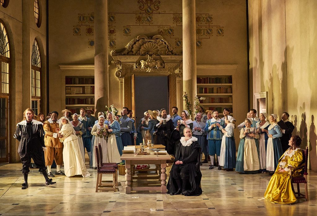 The cast of The Marriage of Figaro in costume in a large hall.