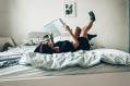 A woman lying on a bed reading a book. Best new books published October 2025 in Australia.