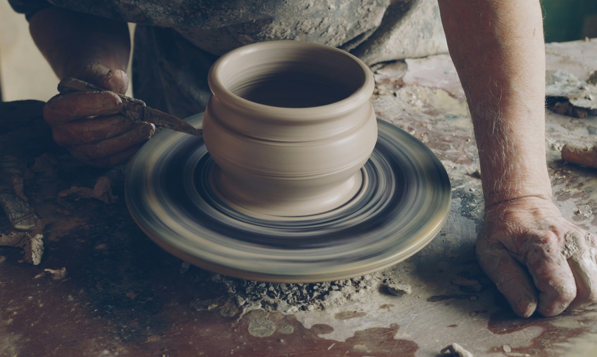 Detail view of a man working on a pot in a ceramic studio. Silicosis