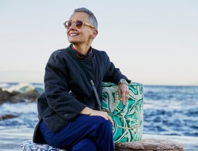 Woman with short grey hair and sunglasses at beach setting. Sophie Tatlow