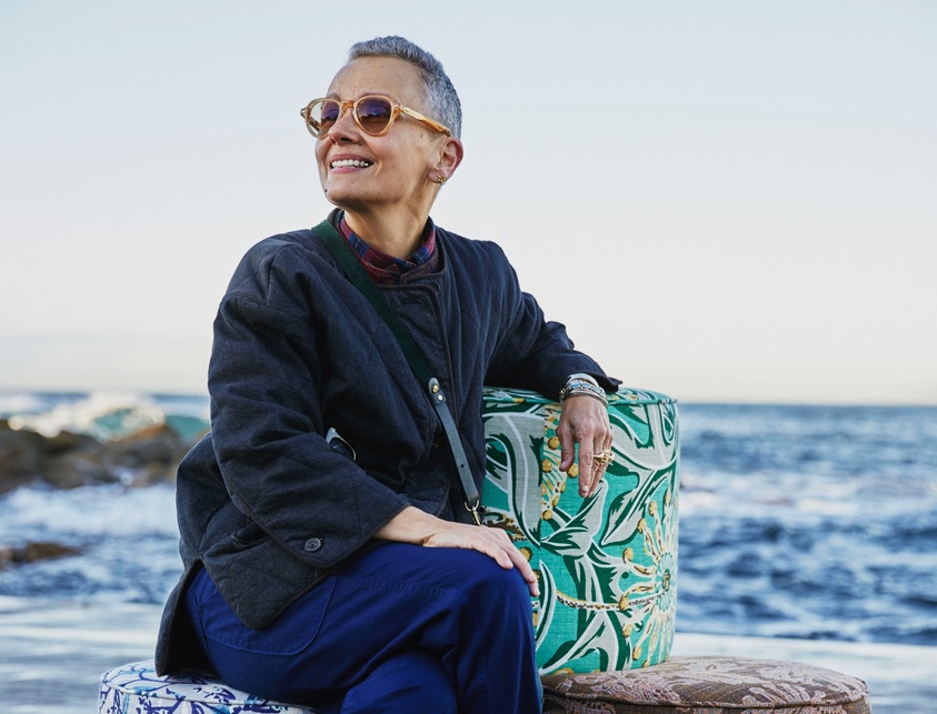 Woman with short grey hair and sunglasses at beach setting. Sophie Tatlow