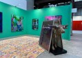 Image of a green art fair display with an ox holding up some paintings. Sydney Contemporary