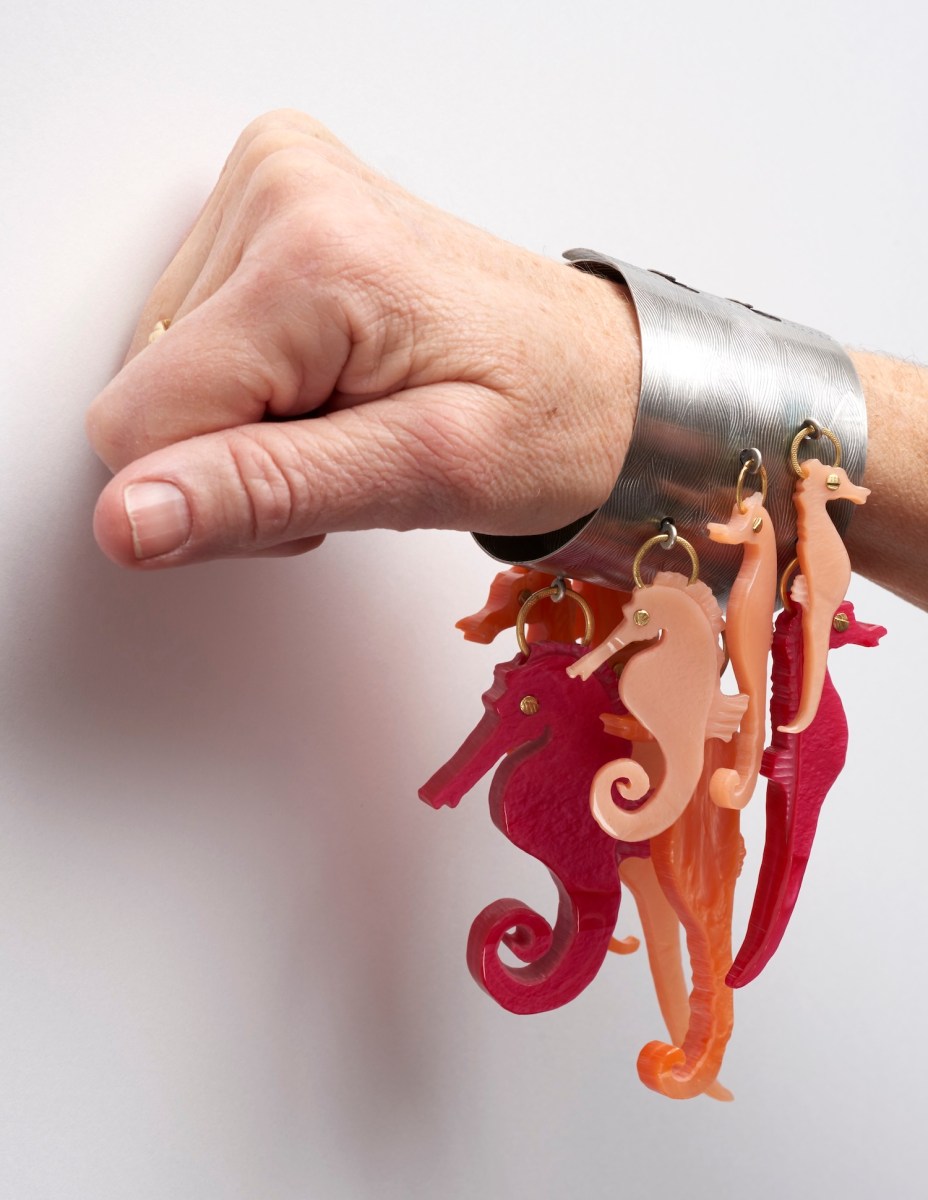 Hand displaying silver bangle with colorful seahorses. Helen Britton