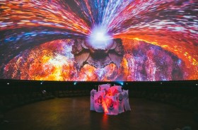 A dome with a light projection and a small group of performers underneath. Art & Bali.
