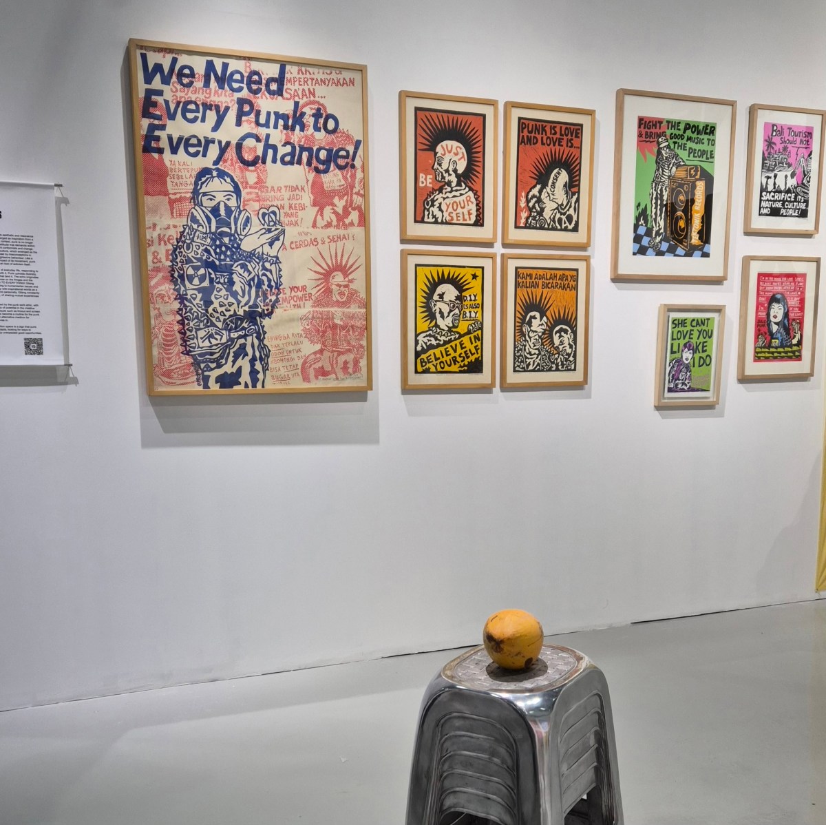 Punk posters with slogans such as ‘WE NEED EVERY PUNK TO EVERY CHANGE!’ And ‘BELIEVE IN YOURSELF’ are displayed on a white wall at Art&Bali 2025. 