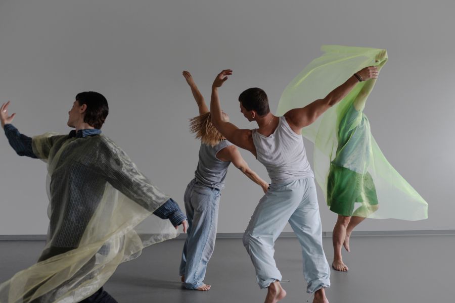 A publicity image for 'Resonance' at IDEA'25.  A dynamic photograph of four contemporary dance practitioners, two of whom are draped in diaphanous, translucent fabric that swirls around them as they dance.  