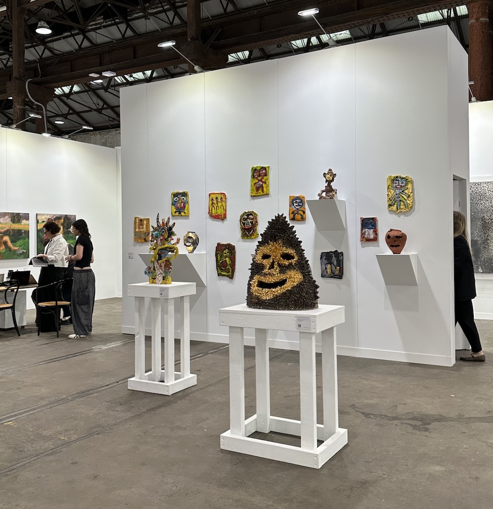 display of messy wall mounted ceramics and one on pedestal with smiley face. Sydney Contemporary