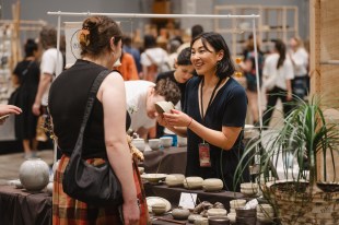 A makers market with a woman selling a ceramic pot to a buyer. Sydney Craft Week
