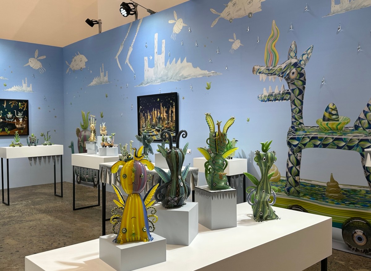 installation view of quirky animals made from glass with blue animated wallpaper in art fair setting. Sydney Contemporary