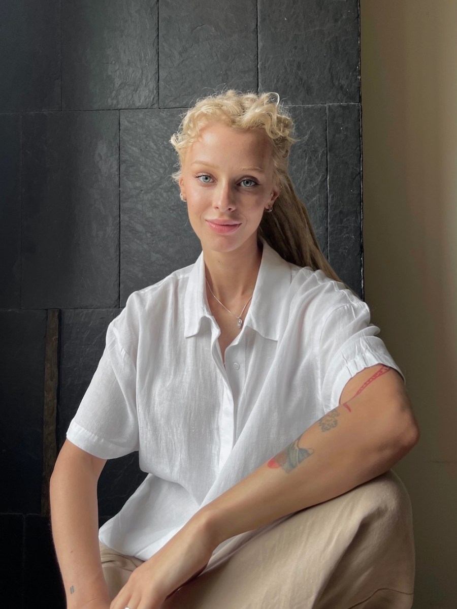 woman with blonde hair and white shirt with tattoo on arm. Homo Faber