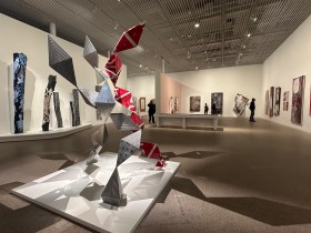 AGNSW staff protest: installation view of an AGNSW exhibition featuring a shiny metal sculpture in the foreground and Aboriginal art (paintings) in the background.