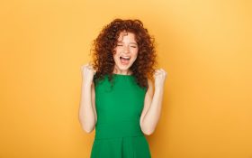 A woman with fists pulled back to her shoulders in an expression of joy. Opportunities.