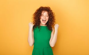 A woman with fists pulled back to her shoulders in an expression of joy. Opportunities.