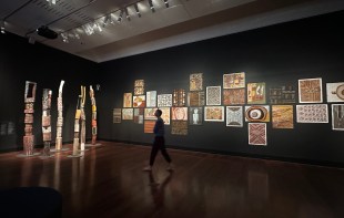 Gallery view of traditional Tiwi Islands and Aboriginal art on black walls. Tarnanthi