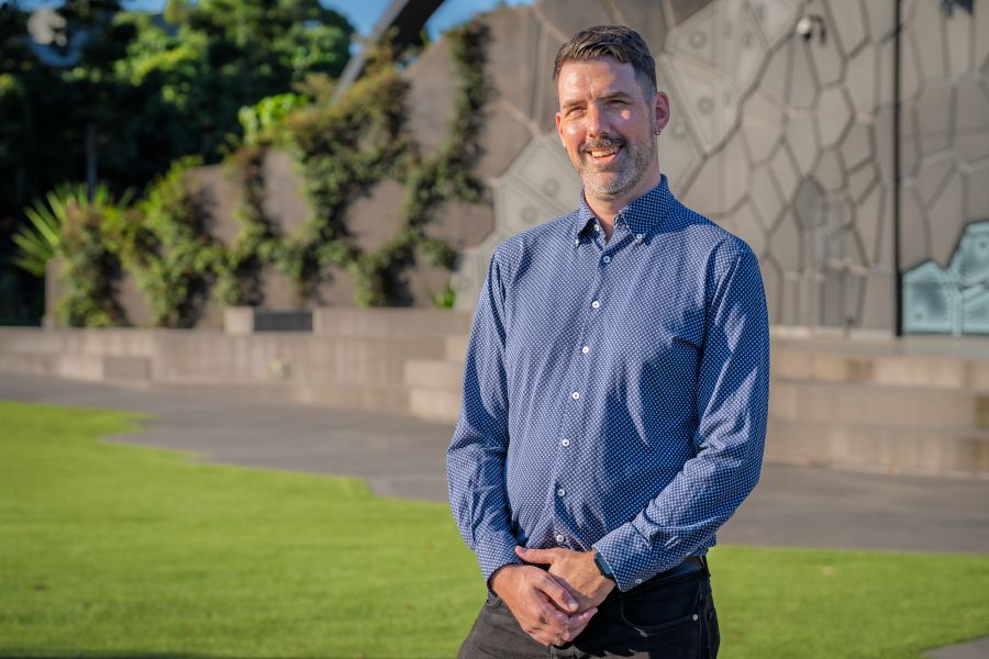 BLEACH* Festival's new Artistic Director, Felix Preval, a fair-skinned man with short brown hair, designer stubble and wearing a blue collared shirt. He stands with his hands loosely clasped in front of him and is smiling. 